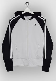 "Adidas full-zip hoodie in white and black. - Size tag: Please always check measurements before buying. Women's M - Measurements (laying flat): Pit to Pit: 20\" Length: 24\" Pit to Cuff: 19\" -Wear: /Please see images for details/ Good vintage condition. Missing drawstring. - Fabric: Polyester *All of our items are preloved pieces so some signs of natural wear and age are to be expected. Please look through the photos carefully to check if the condition is to your satisfaction.  *All efforts are made to show any defects however small imperfections may be missed. In cases that we've missed a major flaw, please remember that we are still human and make mistakes, please contact us first so we can work out any occurred problems together. *We try to describe the sizes as accurately as possible, Sporty White Hooded Jacket For Streetwear, White Track Jacket With Drawstring Hood For Sports, White Sporty Hooded Jacket For Streetwear, White Cotton Track Jacket For Athleisure, White Track Jacket With Adjustable Hood For Sports, White Hoodie Track Jacket With Drawstring, White Casual Track Jacket With Drawstring Hood, White Hooded Jacket With Drawstring For Sports, White Cotton Track Jacket In Sportswear Style