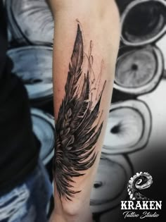 a black and grey feather tattoo on the arm