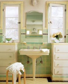 a bathroom with green and white tiles on the walls, two windows, an old fashioned sink and stool