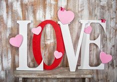 the word love spelled with felt hearts on a wooden shelf in front of a wall