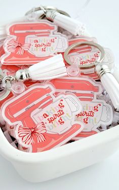 a white bowl filled with lots of key chains and tags on top of each other