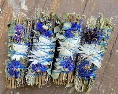 several bundles of dried flowers tied together on wooden planks with blue and white ribbons