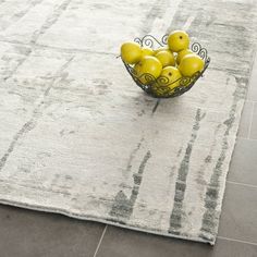 a bowl filled with yellow fruit on top of a rug