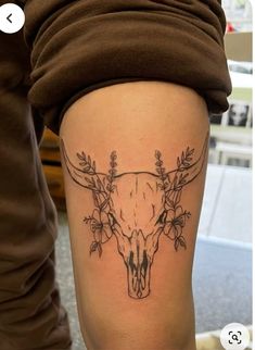 a woman's thigh with a tattoo on it that has an animal skull and flowers