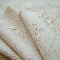 three pieces of white fabric with flowers and pearls on them are laying next to each other