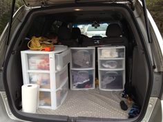 the back end of a car with several storage bins and items in the trunk