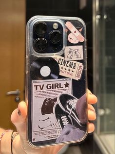 a person holding up a phone case with stickers on it