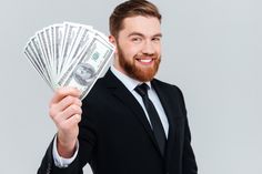 a man in a suit holding money up to his face and smiling at the camera