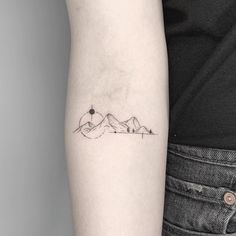 a woman's arm with a small mountain tattoo on the left side of her arm