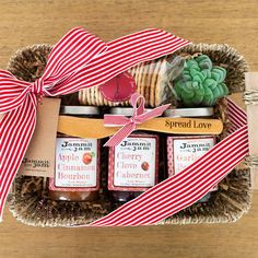 a gift basket with jams, cookies and succulents in it on a table