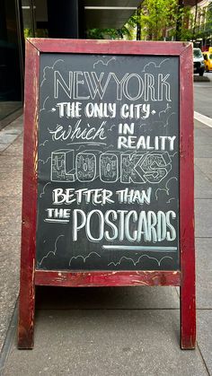 a chalkboard sign on the sidewalk advertising new york, the only city which in reality look better than the postcards