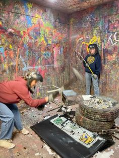 two men are working on graffiti in an old building with lots of paint and debris