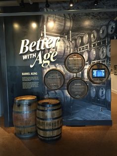 there are three barrels on the floor next to each other in front of a sign that says better with age