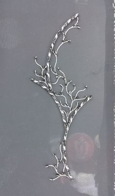 a piece of silver metal on a gray surface with beads and chains hanging from it's sides