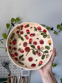 a hand holding up a bowl with tomatoes on it