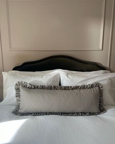 a bed with white sheets and black headboard