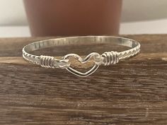 This is a handcrafted bangle/bracelets. It is designed with an oval shape to ensure a proper fit. It is the perfect gift for mothers, sisters, birthdays, daughters, and lovers. This is a simple classy bracelets.  It is  5mm in wide, handcrafted wire-wrapped bangle bracelet, wire wrapped in sterling silver. A dainty, elegant bracelet that can be used as a statement piece. All my materials are14K gold-filled and/or sterling silver and are purchased from reputable jewelers. These bracelets will not tarnish. No plated materials. Wear it every day!   This bracelet can be ordered in 6, 7, 8, or 8.5 and inches. The most common size is 7.5. If this does not match your needs please contact me. When measuring for the bracelet, measure your wrist size.  order your snug wrist size, not your bracelet s Adjustable Silver Heart Bangle Bracelet, Handmade Adjustable Bracelets For Anniversary, Wire Wrapped Bangle Jewelry For Anniversary, Handmade Silver Bracelet For Friendship, Silver Hand Wrapped Bracelets For Friendship, Handmade Silver Friendship Bracelet, Sterling Silver Wire Wrapped Bangle Jewelry, Adjustable Wire Wrapped Bangle As Gift, Adjustable Wire Wrapped Bangle For Gift