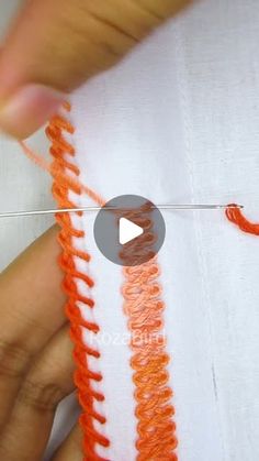 someone is stitching an orange thread on a white piece of fabric that has been sewn