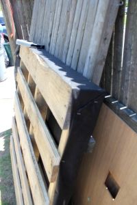 a wooden crate sitting on top of a pile of pallets next to a fence