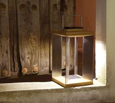 a light that is sitting on top of a wooden table next to a wall with holes in it