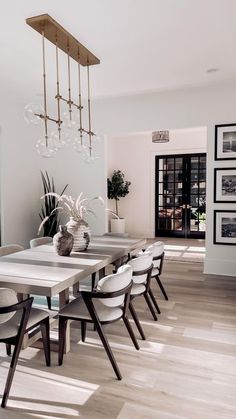 a dining room table with white chairs and a chandelier hanging from the ceiling