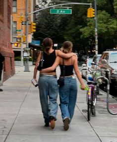 two women walking down the street with their arms around each other's back,