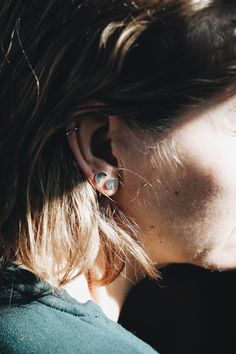 a close up of a person with ear piercings on their ears and in the sun