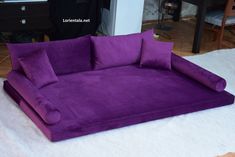 a purple couch sitting on top of a white rug