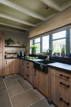 a kitchen with wooden cabinets and black counter tops next to a large window that looks out onto the outdoors