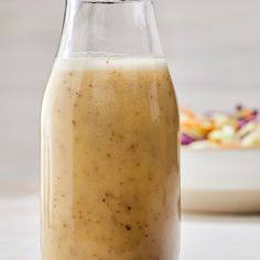 a glass bottle filled with liquid sitting on top of a table next to a bowl