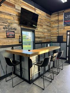 the inside of a restaurant with wooden walls and black barstools, televisions on the wall