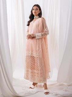 Defining our mesmerizing peach ensemble, which carries you to another dimension of ethereal beauty. Your look effortlessly refines everywhere you go, owing the exquisite cut work on the front of the apparel, which is meticulously crafted with threads, sequence jaal and pattern to add a touch of glamour and refinement. The coordinated pants also feature matching handwork, and the net dupatta is adorned with white embroidery that perfectly contrasts with your apparel. Embrace the romance of summer Zainab Chottani, Another Dimension, Sana Safinaz, Maria B, Net Dupatta, Ethereal Beauty, Gold Threads, White Embroidery, Cut Work