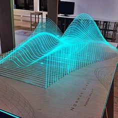 an illuminated display in the shape of a wave on a table with chairs and televisions behind it