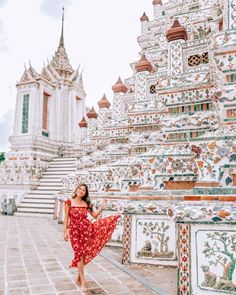 a woman in a red dress standing next to a white and green building with ornate designs on it