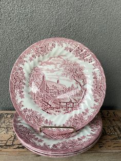 three pink and white plates stacked on top of each other in front of a gray wall