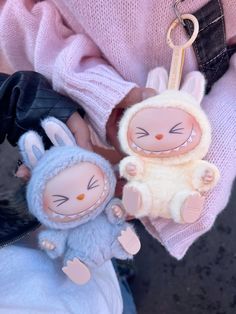 two stuffed animals sitting next to each other on a person's arm with a keychain