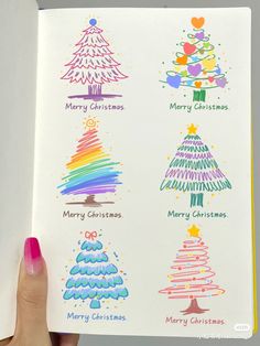 a hand holding an open christmas card with different trees on it and the words merry christmas