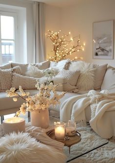 a living room filled with lots of white furniture and candles on top of a coffee table