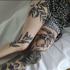 a woman laying on top of a bed with tattoos on her arms and legs,