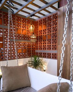 a white couch sitting under a wooden pergolated wall next to a potted plant