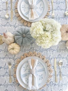 the table is set with plates, silverware, and white hydrangea flowers