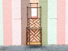 a tall wooden chair sitting in front of a wall with a mirror on it's back