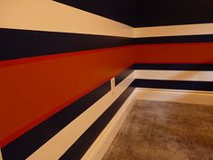 an empty room with black, white and red stripes painted on the wall behind it