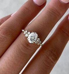 a woman's hand with a diamond ring on top of her finger and two diamonds in the middle