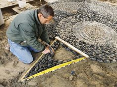 a man kneeling down next to a pile of tires on top of dirt covered ground