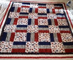 a red, white and blue quilt sitting on top of a bed