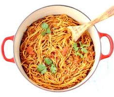 a red pot filled with spaghetti and garnished with cilantro