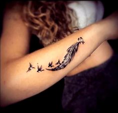 a woman with a tattoo on her arm holding a bird and feather - shaped object