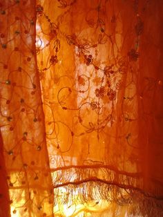 an orange curtain with small flowers on it