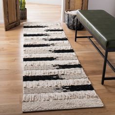 a white and black rug on the floor next to a green bench with a potted plant